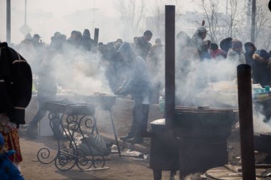Uralsk (Oral), Kazakistan, 22.03.2024 - Kazakistan 'da Nauryz tatili. Barbeküden çıkan dumandaki bir kalabalık..