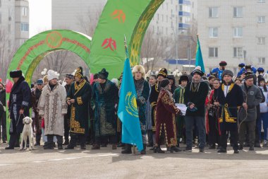 Uralsk (Oral), Kazakistan, 22.03.2024 - Kazakistan 'da Nauryz tatili. Nauryz bayramında Kazak milli kostümlü insanlar. Kazak bayrağı taşıyan adam..