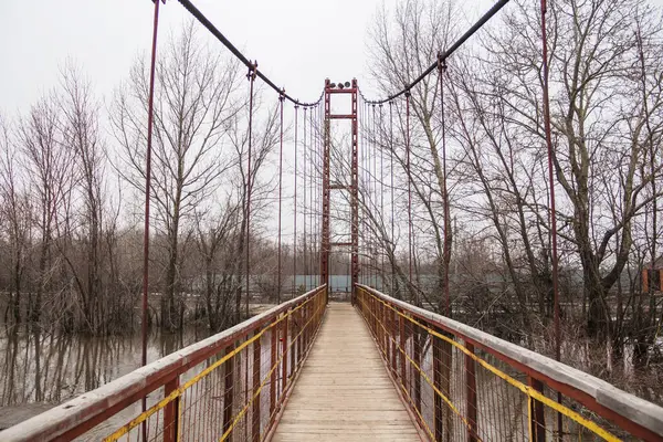 Suspension pedestrian bridge over the Chagan River in Uralsk. Suspension bridge over the river.