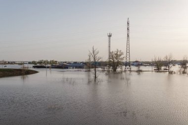 Kazakistan 'da sel. Bir köy suyla doldu. Nehir kıyılarından taştı. Tarlada eriyen su. Sel suyunda elektrik hattı desteği.