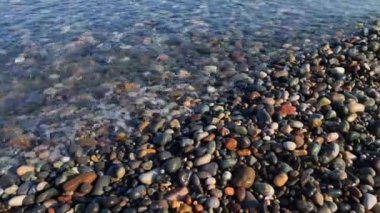 Dalgalar kıyıya büyük renkli taşlarla vuruyor. Batumi şehrindeki Karadeniz 'in çakıl taşı plajı. Georgia 'ya git. Batumi 'de deniz tatili.