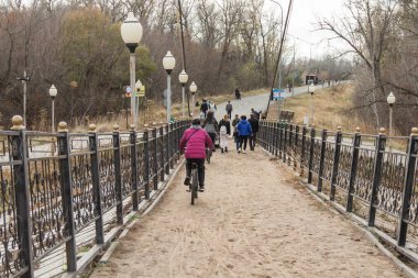 Uralsk, Oral, Kazakistan (Kazakistan), 20.10.2024: Bir bisikletçi ve insanlar Uralsk kentindeki bir kültür ve dinlenme parkında tamir halindeki yaya köprüsünde.