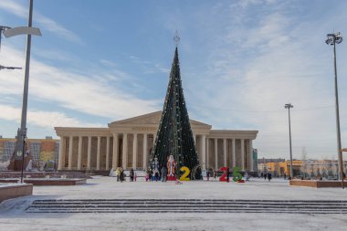 Uralsk, Kazakistan (Kazakistan), 28.12.2024: Yeni Yıl Ağacı, Birinci Başkan Meydanı 'ndaki Peder Frost ve Kar Bakiresi. Yeni yıl ağacının arkasındaki Atameken Oner Ordasy binaları.
