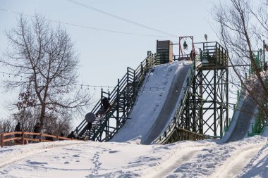 Uralsk, Kazakistan (Kazakistan), 2.03.2025: Uralsk 'taki Svetlyachok dinlenme merkezinde yüksek kış slaytları. Kış eğlencesi Kış Slaytları.