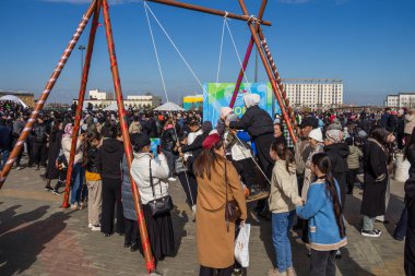 Uralsk, Kazakistan (Kazakistan), 22.03.2025: Nauryz bayramı kutlamaları sırasında çocuklar Altybakan salıncağına biniyor.