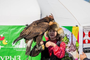 Uralsk, Kazakistan (Kazakistan), 22.03.2025: Nauryz bayramı sırasında bir kız altın kartalla fotoğraf çekiyor.
