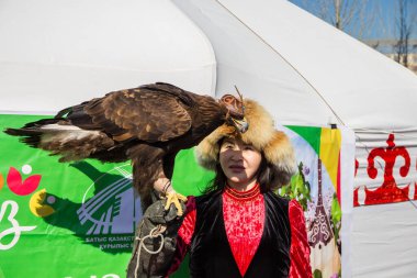 Uralsk, Kazakistan (Kazakistan), 22.03.2025: Nauryz bayramı sırasında bir kız altın kartalla fotoğraf çekiyor.