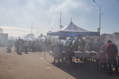 Uralsk, Kazakistan (Kazakistan), 22.03.2025: Meydan barbekü dumanlarıyla kaplıdır. İnsanlar Nauryz kutlamaları sırasında dışarıda dumanın içinde yemek yiyorlar. Kazakistan 'da bahar ekinoksu günü.