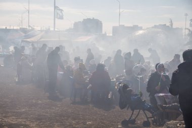 Uralsk, Kazakistan (Kazakistan), 22.03.2025: Meydan barbekü dumanlarıyla kaplıdır. İnsanlar Nauryz bayramı kutlamaları sırasında sokakta barbekü yerken dumanla kaplanıyor..
