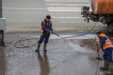 Uralsk, Kazakistan (Kazakistan), 14.04.2025: Belediye çalışanları kaldırımdaki kaldırım taşlarını yıkayıp süpürüyorlar. Kazakistan şehrini misafirlerin gelişi için hazırlıyorum. Kaldırımı temizleyip yıkıyorum..