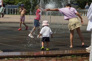 Uralsk, Kazakistan (Kazakistan), 8 Haziran 2025 - Çocuklar sıcak bir yaz gününde şehir çeşmesinde oynuyorlar, serin su ve neşeli iletişimin tadını çıkarıyorlar.