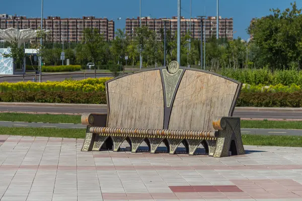 Astana 'daki Merkez Cami Meydanı' ndaki dekoratif bir bank. Yeşillik ve konut binalarına karşı..