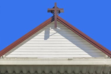 St. Saviour 'un arka cephesinde beyaz boyalı, yatay ahşap çatallar ve açık mavi gökyüzüne karşı kahverengi renkli çifte haç var. Kuranda-Queensland-Avustralya.