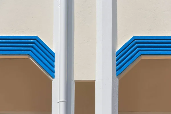 Detail of the Art Deco facade of a two-story, reinforced concrete building on the Edith and Owen streets corner with slender white columns and blue grooved decoration. Innisfail-Queensland-Australia.