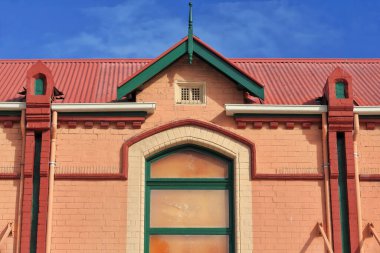 Federation style brick building dating from the 1890s painted orange-red-yellow-green with blind window on the south side of The Corso pedestrian street. Manly suburb-Sydney-New South Wales-Australia.
