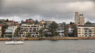 North Head yarımadası kıyısı boyunca Manly Cove 'a bakan liman binaları ve Manly' den Sydney feribotuna kadar demirlemiş yelkenliler var. Sydney Limanı-NSW-Avustralya