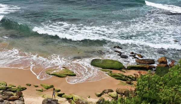 ノッツ アベニューから見えるボンダイ ビーチ南西端の砂から突き出た緑藻で覆われた岩の上に突き出た穏やかな波の景色 シドニー ニューサウスウェールズ オーストラリア州 画像の中の偶然の人 — ストック写真