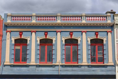 Viktorya dönemi ticari teras ön cephesi üst katta balyoz parapet ile mavi-kırmızı krem boyanmış ve Sturt Caddesi 'nin güney tarafındaki yaya yolu ön tarafındaki tente üzerinde kantille kaplanmış. Ballarat-VIC-Avustralya.