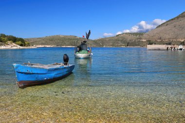Eski, fiberglas balıkçı tekneleri İyon Denizi 'ndeki Porto Palermo Körfezi' nin sığ sularında karaya vurmuş ve demirlemiş. Himare-Arnavutluk.