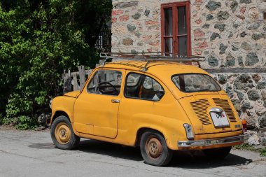 Vevcani, N.Macedonia-20 Nisan 2019: Eski Yugoslav komünist döneminden kalma klasik turuncu-sarı Zastava 750 LE arabası, yolun başında yerel bir evin önüne park edilmiş ve yerel yaylara doğru gidiyor..
