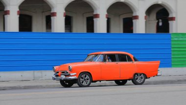 Havana, Küba-07 Ekim 2019: Kırmızı-turuncu eski Amerikan klasik arabası -almendron, yank tank- Dodge Kingsway Custom 4 kapılı Sedan 1956 'dan Paseo del Prado boyunca metal bir çitin yanından geçiyor..