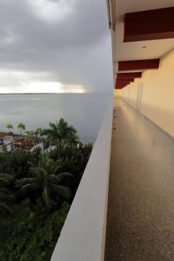 Cienfuegos, Cuba-October 11, 2019: Westward view from the Jagua Hotel open gallery at late afternoon after heavy tropical rain of the stormy sky over Jagua Bay. Punta Gorda Peninsula-city's south tip. clipart