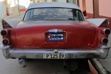 Trinidad, Küba-12 Ekim 2019: Arka manzara, bordo kırmızısı ve beyaz eski Amerikan klasik arabası -almendron, yank tank- Dodge Royal 4 kapılı Sedan 1958 yılında Plaza Belediye Başkanı Meydanı 'nın bir caddesinde konuşlandırıldı.