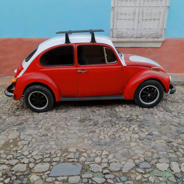 Old 2-door, red and white European economy classic car -Volkswagen Type 1, so-called Beetle- on Calle Amargura Street number 70. Trinidad-Cuba-270 clipart