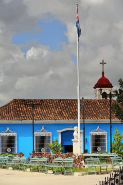 Sancti Spiritus, Cuba-October 15, 2019: The Presbyterian church belfry jutting over the blue walled, one-storey building of the former Pedro de Castaneda de Rojas mansion, today the Provincial Museum. clipart