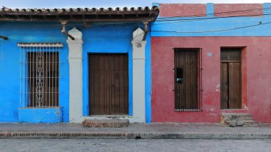 Camaguey, Küba-15 Ekim 2019: XVIII. Yüzyıl Plaza del Carmen Meydanı kuzey tarafındaki sömürge evlerinin cepheleri, bir tanesi işlenmiş demir ızgarayla maviye boyanmış, bir diğeri mavi çizgili kestane rengi..
