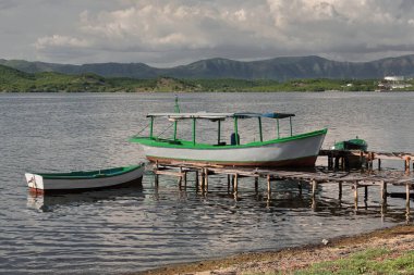Balıkçı tekneleri ve sürat tekneleri körfezin S bölgesindeki Cayo Granma Key 'in NW kıyısından çıkan ahşap rıhtımlara demirlemiş durumda. Arka planda N bölgesinin endüstriyel tesisleri var. Santiago-Küba.
