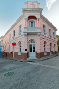 Santiago, Cuba-October 20, 2019: Eclectic style, two-story pink building from the early 1900s at the Calles Francisco Aguilera and General Lacret Streets northeast chamfered, parapet-topped corner. clipart