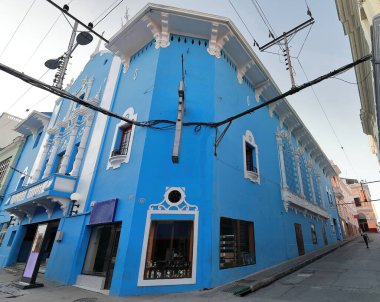 Santiago, Cuba-October 20, 2019: Chamfer facade, Enramadas and General Lacret Streets corner, azure-blue painted outer wall of the Eclectic style Cine Cuba movie theater building from the early 1900s. clipart