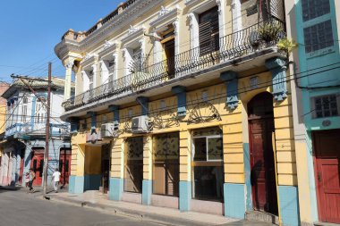Santiago, Küba-20 Ekim 2019 Calle Francisco Aguilera Caddesi 'nin güney cephesi, iki katlı eklektik bina, sarı, beyaz ve mavi pervazlarla boyanmış, tam uzunluktaki balkonda demir parmaklıklar..