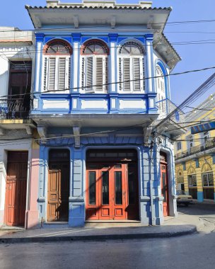 Santiago, Küba-20 Ekim 2019 Calle Francisco Aguilera Caddesi 'nin güney cephesi iki katlı eklektik bina, mavi ve beyaz kahverengi ve kırmızımsı ahşap kapılar ve fanlight transom pencerelerle boyanmış..