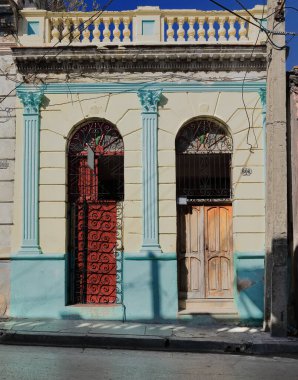 Santiago, Küba, 20 Ekim 2019: Soluk yeşil pervazlı, boyanmamış ve kırmızı ahşap kapılı soluk sarı duvar, San Agustin-Donato Marmol Caddesi 'nde doğuya bakan eklektik stil binası..