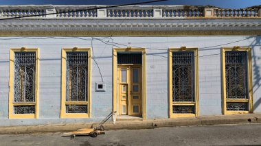 Santiago, Küba, 20 Ekim 2019: Sarı perdeli gri-mavi duvar, gri ve sarı ahşap kapı ve pencere panjurları, Heredia Caddesi 'ndeki yenilenmiş eklektik binanın güneye bakan cephesi.