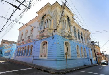 Santiago, Küba-20 Ekim 2019: Calles Heredia ve Calvario Caddeleri 'ndeki ikiz cephe iki katlı, mavi ve beyaz eklektik lojistik bina ve küçük balkonlar, fanlight transom pencereler.