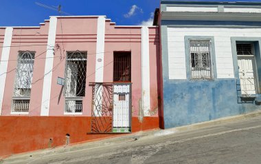 Santiago, Küba-20 Ekim 2019: Beyaz pervaz ve kırmızı dado duvarlı pembe, mavi pervazlı beyaz ve dado ön cepheli, Bartolome Maso Caddesi 'ndeki tek katlı konak evleri, çift sayılı batı tarafında..