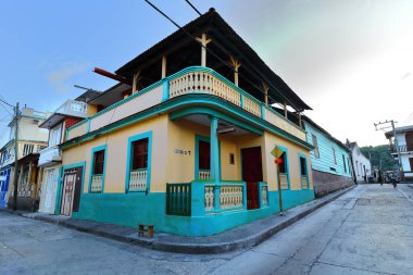 Baracoa, Küba-21 Ekim 2019: Calles Ciro Frias ve Felix Ruene Caddelerinin iki katlı, nane yeşili ve şeftali kremalı eklektik tarzda 2nd.zemin kattaki balkonda ikiz cephe.