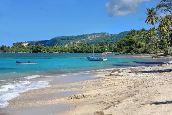 stock image Shallow turquoise waters and gentle waves caress the sand strip at Playa Manglito Beach protected by offshore sandbanks and reefs and lined with palm trees, to the east of the city. Baracoa-Cuba.