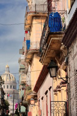 Havana, Cuba-October 26, 2019: Old houses on Calle Brasil or Teniente Rey Street north side with the National Capitol -Capitolio Nacional- building from AD 1926-1929, renovated in 2019, in background. clipart