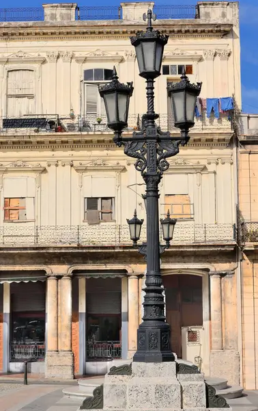 stock image Havana, Cuba-October 26, 2019: Artistic street lamp on Paseo del Prado and east-facing cream-colored facade of a three-story early 1900s Eclectic building at the Neptuno Street corner, Habana Centro.