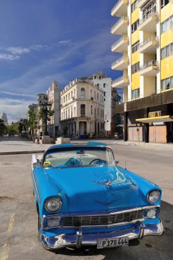 Havana, Cuba-October 27, 2019: Blue with white old American classic car -Chevrolet Bel Air 2 door Convertible from 1956- stationed on Paseo del Prado promenade facing the Edificio Prado 20 building. clipart