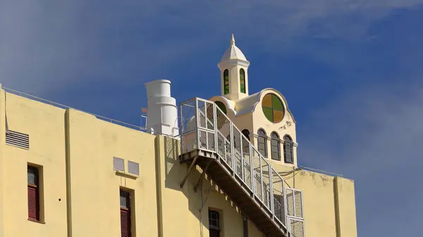 stock image Havana, Cuba-October 27, 2019: Yellow-painted modern building with rooftop lantern on cross-shaped body featuring circular colored wall-mounted skylights and metal exterior stairway on the facade.