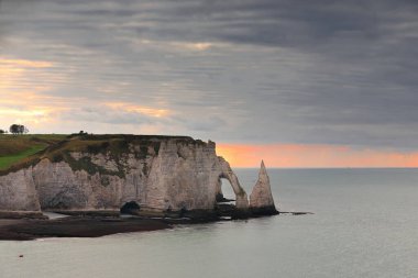 Erken gün batımı renkli gökyüzü, Falaise d 'Amont uçurumundan batıya doğru gelgit kayalıklarına, beyaz tebeşir Falaise d' Aval Cliff, Porte d 'Aval Arch, Aiguille Creuse Needle. Etretat-Normandiya-Fransa.
