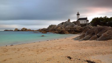 Brignogan, France-October 23, 2020: Southwest-to-northeast view, Phare de Pontusval Lighthouse at dawn from the rocks across the Plage du Phare-Lighthouse Beach in Plouneour-Brignogan-Plages commune. clipart