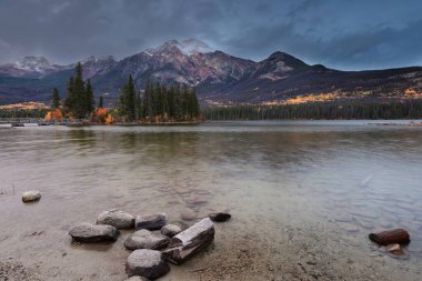 Piramit Gölü üzerinde bulutlu bir şafak, piramit adasına tahta bir köprü ile bağlı Victoria Cross Sıradağları tepeleri: Piramit Dağı (sağda) ve Cairngorm (en solda). Jasper NP-AB-Kanada.