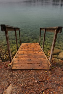 0 '4 km2' ye inen küçük ahşap merdiven, buzulla beslenen Beauvert Gölü Zümrüt yeşil suları, bulutlu ve yağmurlu bir öğleden sonra, göl yatağını şeffaflaştırıyor. Jasper NP-Alberta-Kanada.