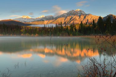 Oldukça açık bir şafağın uzun pozlama görüntüsü: Patricia Lake ile piramit (ortada) ve en soldaki Cairngorm Dağları (en soldaki) gölün kristal berrak sularına yansımaktadır. Jasper NP-Alberta-Kanada.